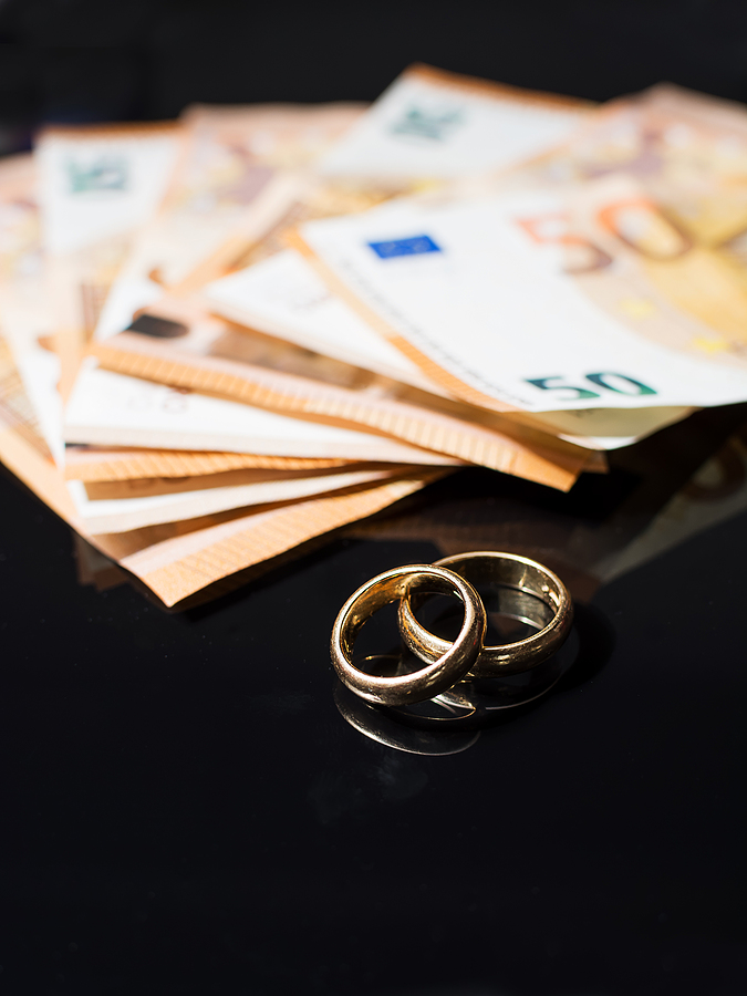 Two Wedding rings and some banknotes on the white table